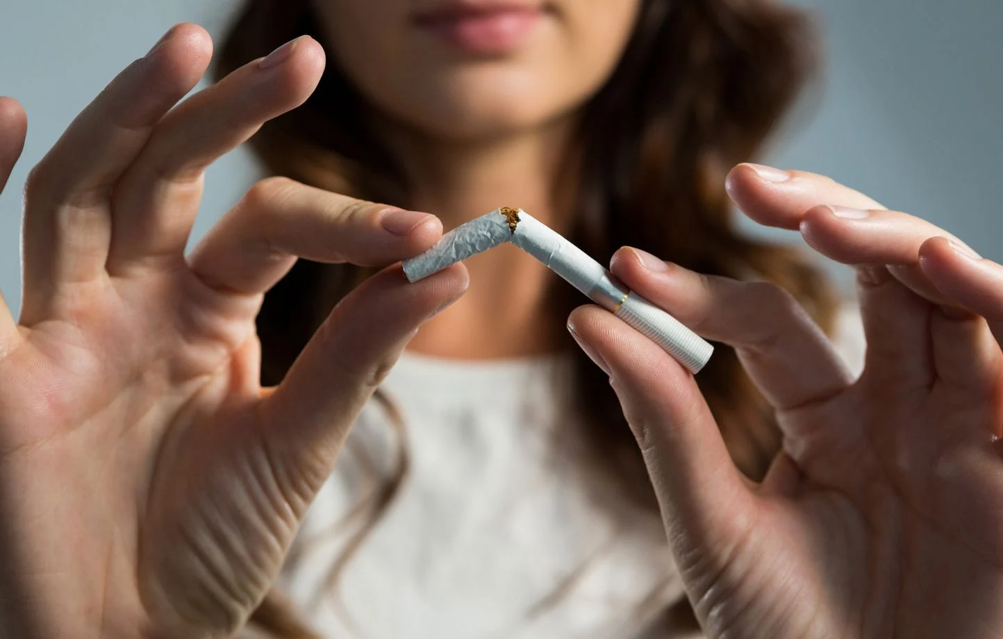 une femme casse une cigarette en deux