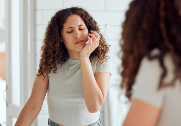 Image d’une femme à l’expression douloureuse, se tenant la mâchoire car souffrant des dents