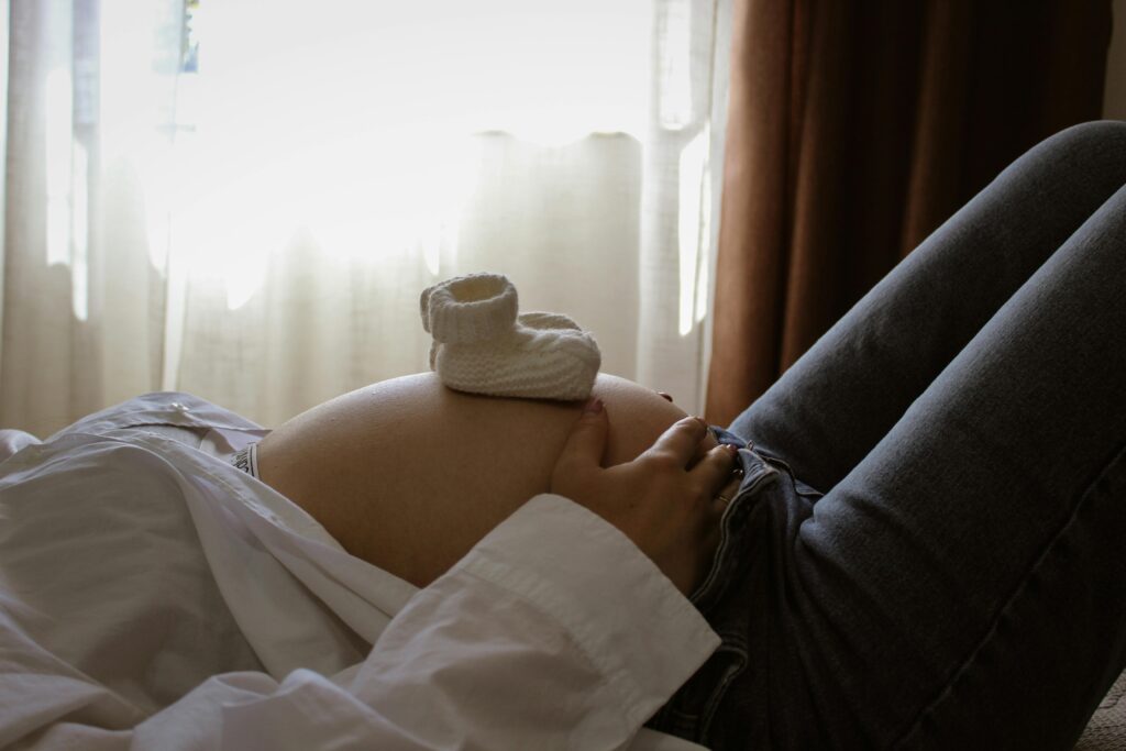 Accueil illustration d'une femme enceinte, allongée, avec des chaussons de bébé posés sur son ventre rebondi