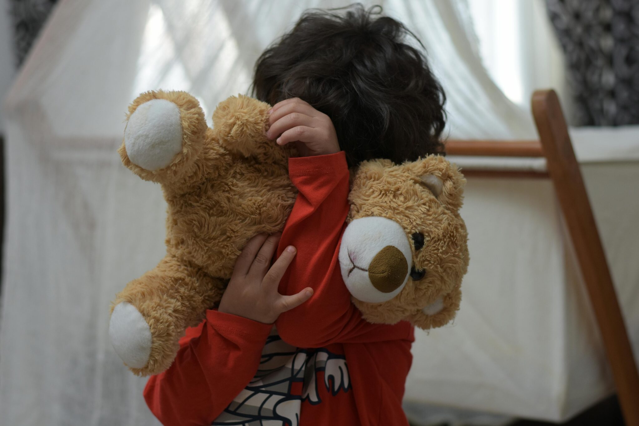 Un enfant se cache derrière un gros ours en peluche