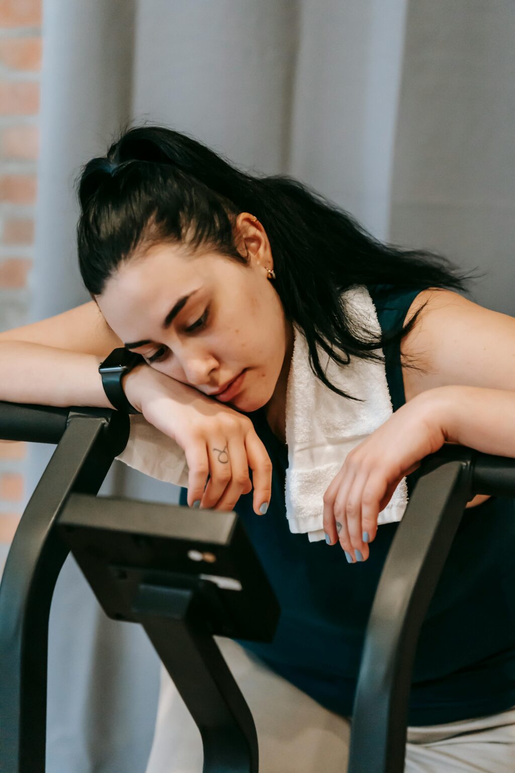 Femme fatiguée, la tête posée sur le haut d'une machine à la salle de sport