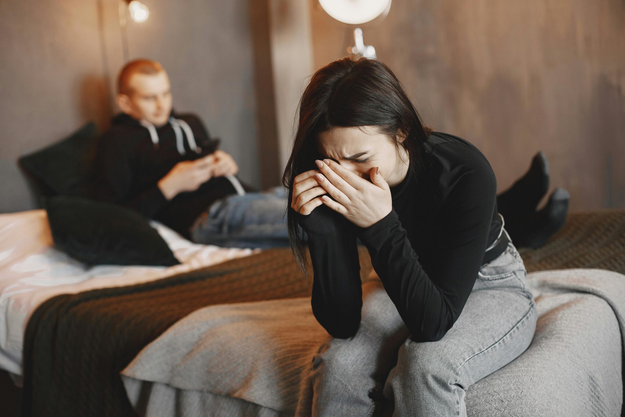 Un couple vit une rupture amoureuse, la femme est en pleurs tandis que son conjoint navigue sur son téléphone.