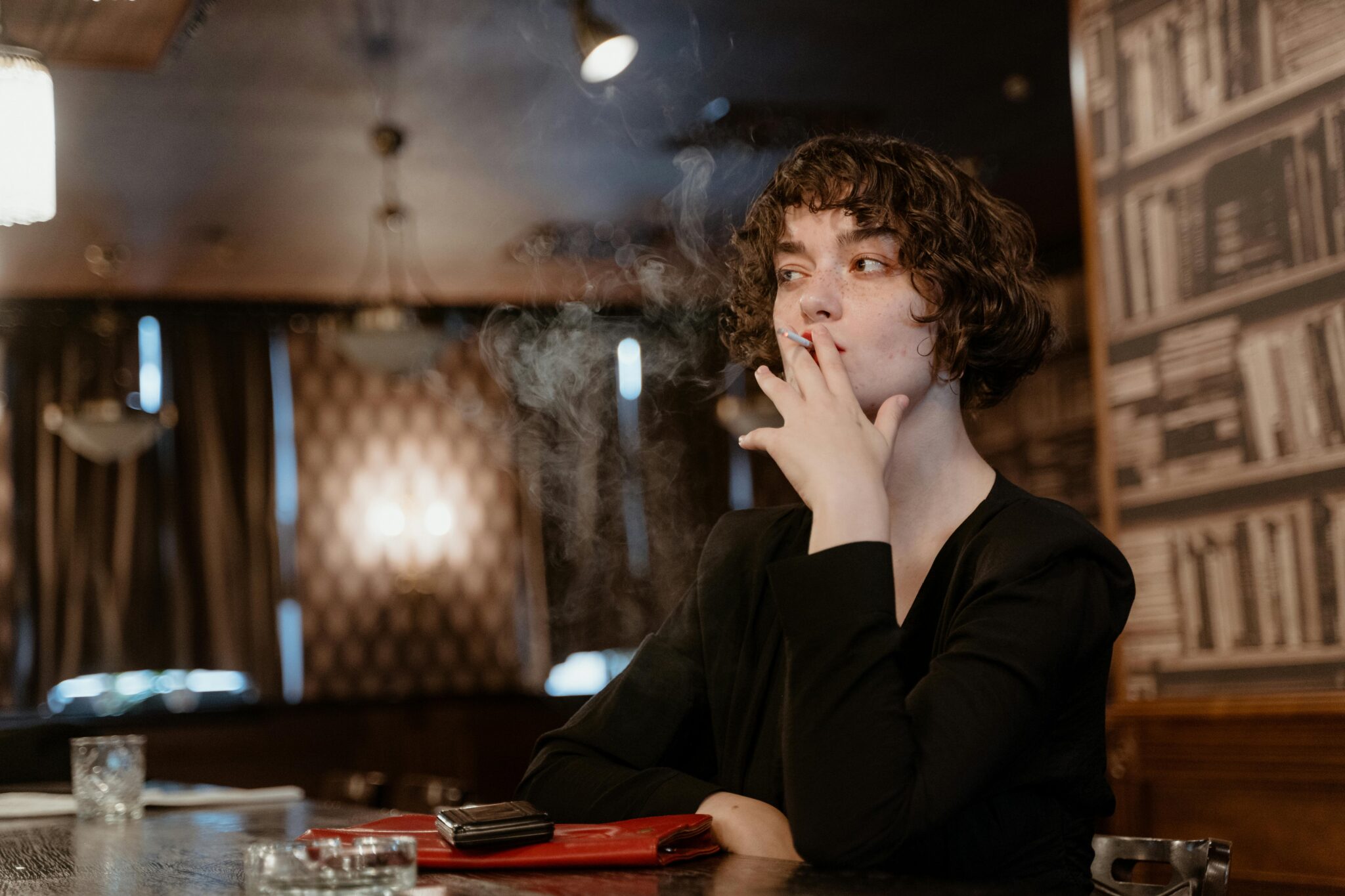 femme assise à table, fumant une cigarette